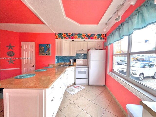 kitchen with light tile patterned flooring, tasteful backsplash, white cabinets, rail lighting, and white appliances