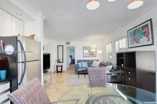 living room featuring light tile patterned flooring, a textured ceiling, and ornamental molding