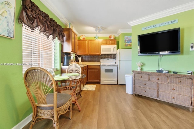 kitchen featuring crown molding, light wood-type flooring, white appliances, sink, and backsplash