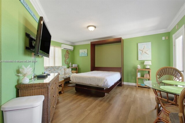 bedroom featuring a wall mounted AC, ornamental molding, and hardwood / wood-style floors