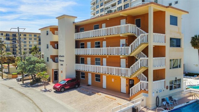 view of building exterior featuring central AC unit and a community pool