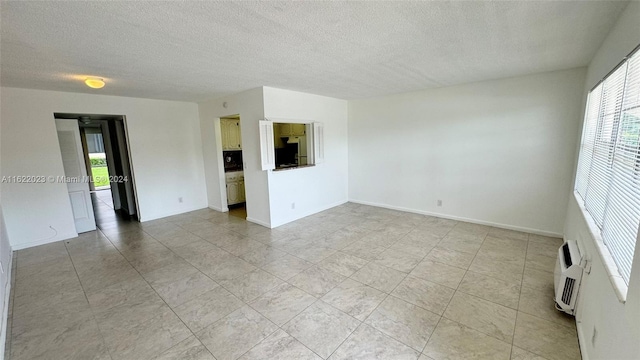 spare room featuring a wall unit AC and a textured ceiling