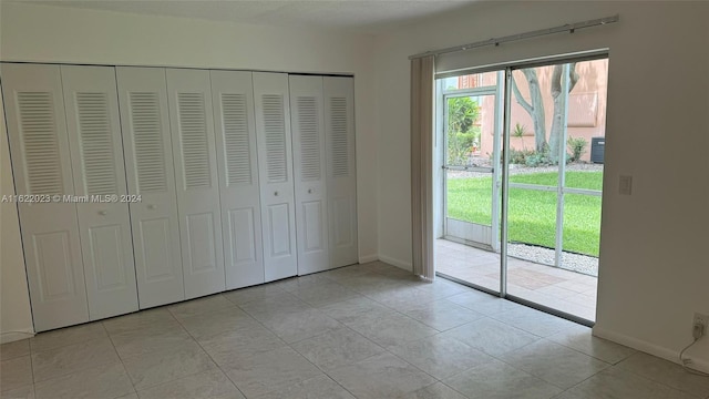 unfurnished bedroom with light tile patterned flooring, access to exterior, and a closet