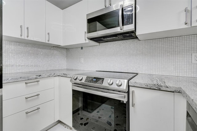 kitchen with white cabinetry, stainless steel appliances, light stone countertops, and tasteful backsplash