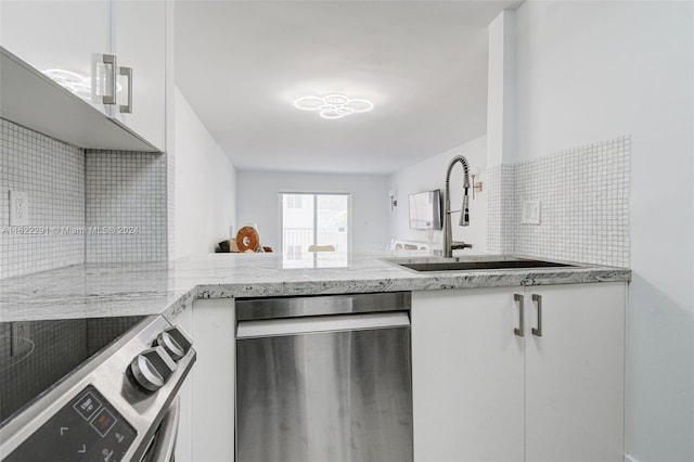 kitchen with decorative backsplash, white cabinets, light stone countertops, sink, and stainless steel appliances