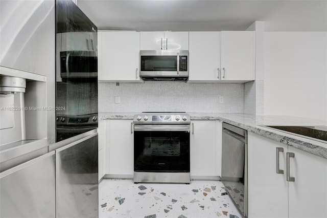 kitchen with white cabinetry, light stone counters, stainless steel appliances, and backsplash