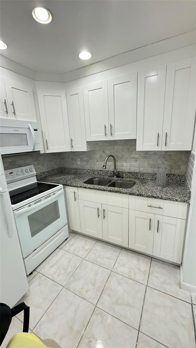 kitchen featuring white appliances, sink, white cabinetry, dark stone counters, and tasteful backsplash