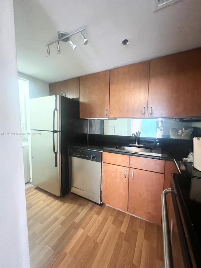 kitchen featuring sink, appliances with stainless steel finishes, light wood-type flooring, and track lighting