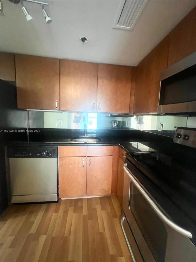 kitchen featuring sink, appliances with stainless steel finishes, light hardwood / wood-style flooring, and rail lighting