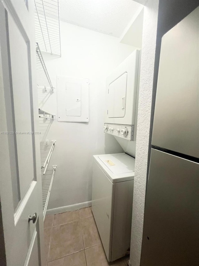 washroom featuring light tile patterned flooring, stacked washer and clothes dryer, and electric panel