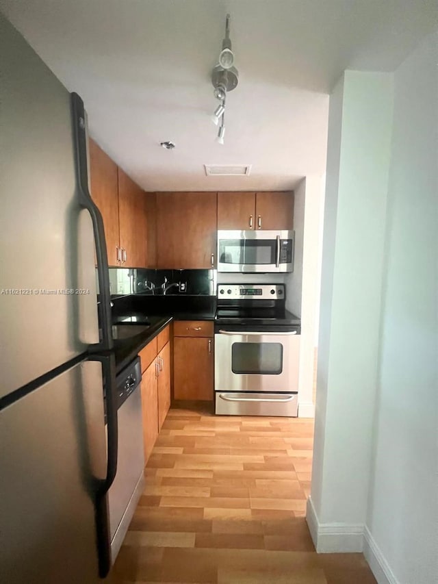 kitchen with track lighting, appliances with stainless steel finishes, and light wood-type flooring