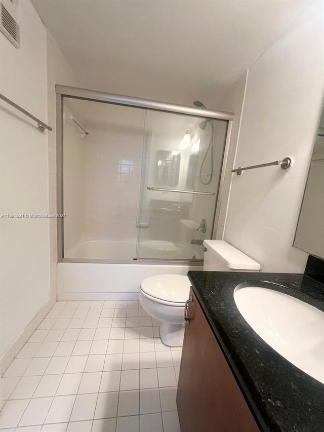 full bathroom with tile patterned flooring, bath / shower combo with glass door, toilet, and vanity