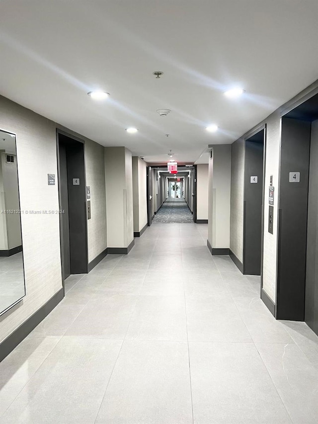 hallway featuring elevator and light tile patterned floors