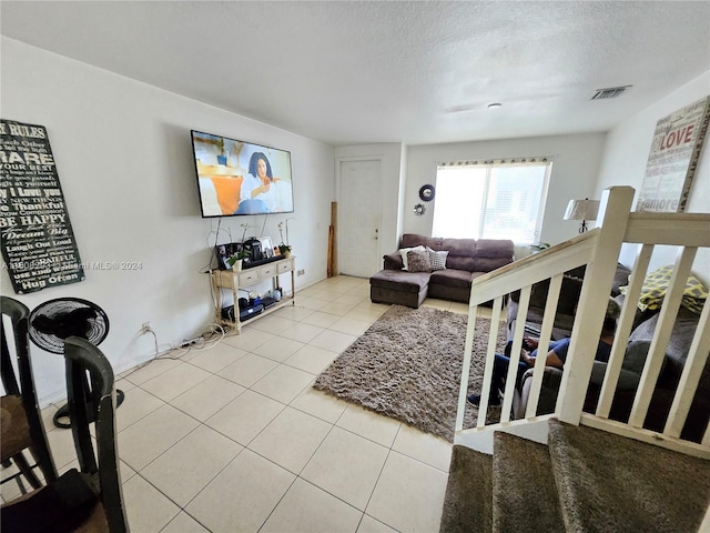 living room with a textured ceiling and light tile patterned flooring