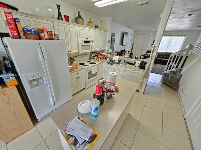 kitchen with kitchen peninsula, white appliances, and light tile patterned flooring