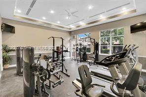 gym featuring a tray ceiling and ceiling fan