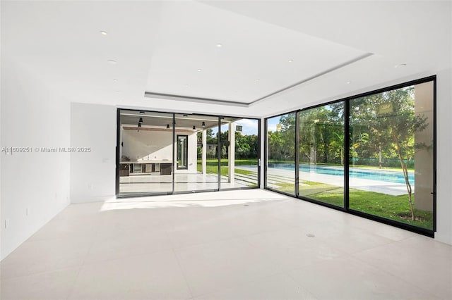 empty room with light tile patterned flooring, floor to ceiling windows, and a tray ceiling