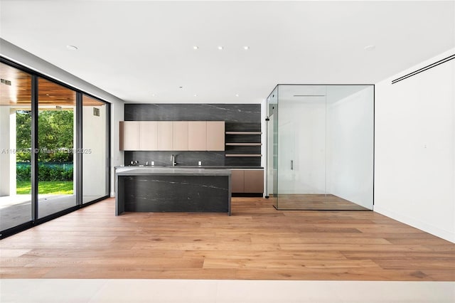 kitchen with sink, backsplash, a wall of windows, and light hardwood / wood-style flooring