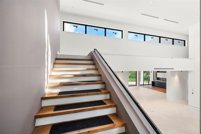 stairway featuring a towering ceiling