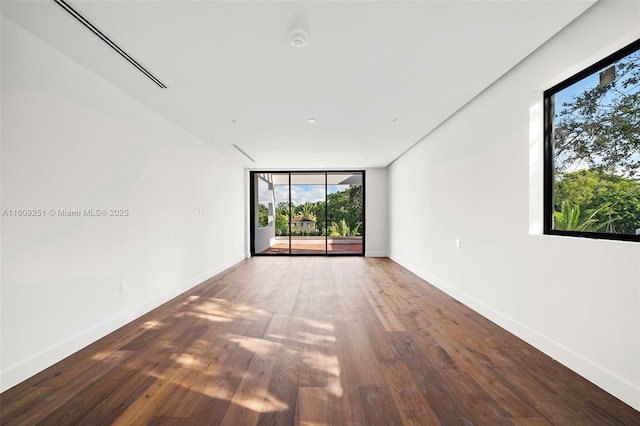 spare room with expansive windows and hardwood / wood-style floors