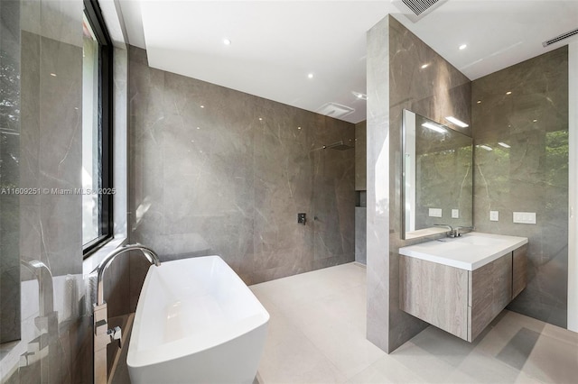 bathroom with tile walls, vanity, and independent shower and bath