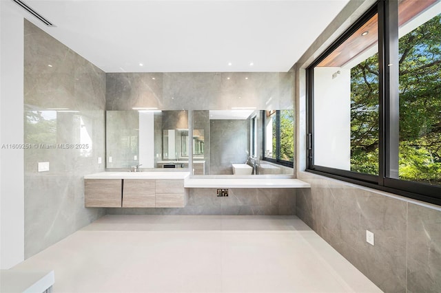 bathroom featuring vanity, a wealth of natural light, and tile walls