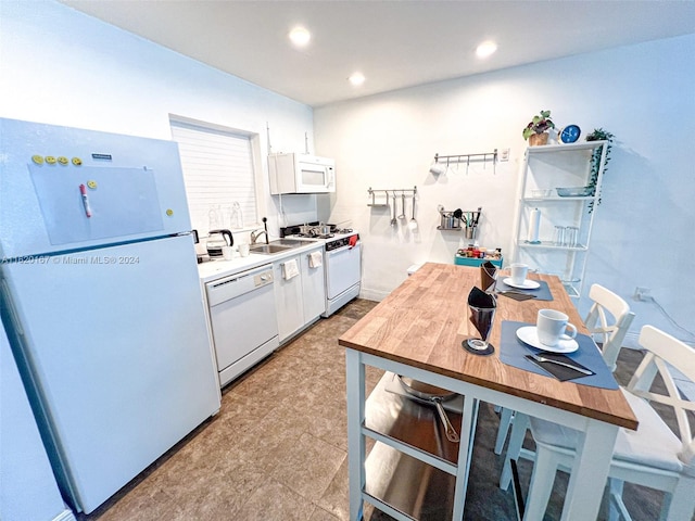 kitchen with white cabinets, butcher block countertops, white appliances, and sink