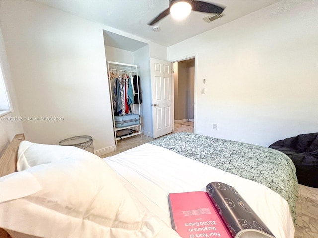 tiled bedroom featuring ceiling fan and a closet