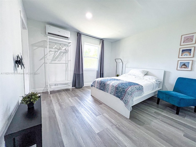 bedroom with hardwood / wood-style floors and a wall mounted air conditioner