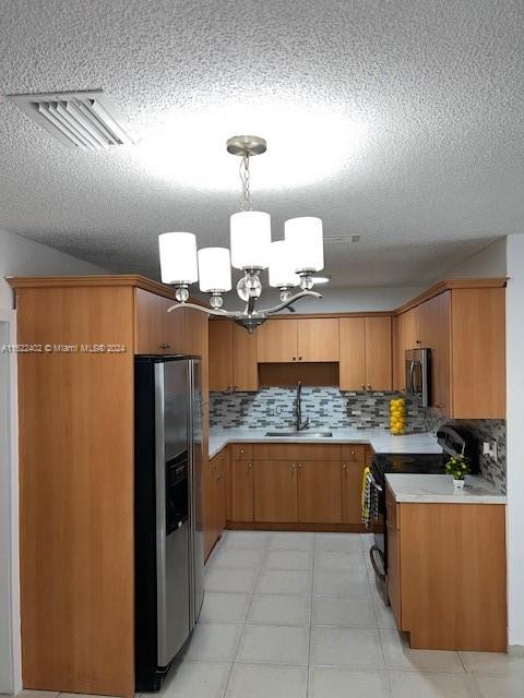 kitchen featuring appliances with stainless steel finishes, light tile patterned floors, decorative backsplash, and sink