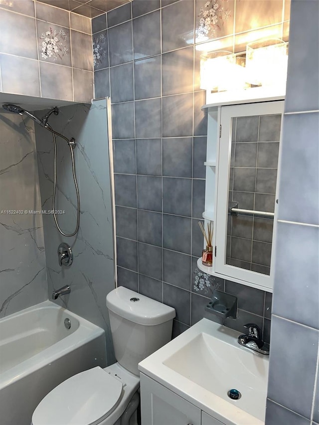 full bathroom featuring vanity, tiled shower / bath, tile walls, and toilet