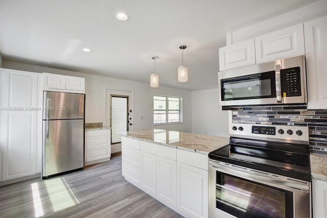 kitchen with appliances with stainless steel finishes, light hardwood / wood-style flooring, white cabinetry, and pendant lighting