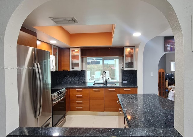 kitchen featuring light tile patterned flooring, backsplash, sink, dark stone countertops, and stainless steel appliances