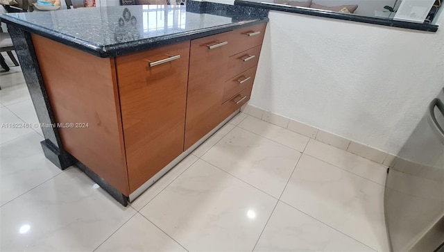 interior space with light tile patterned flooring and dark stone countertops