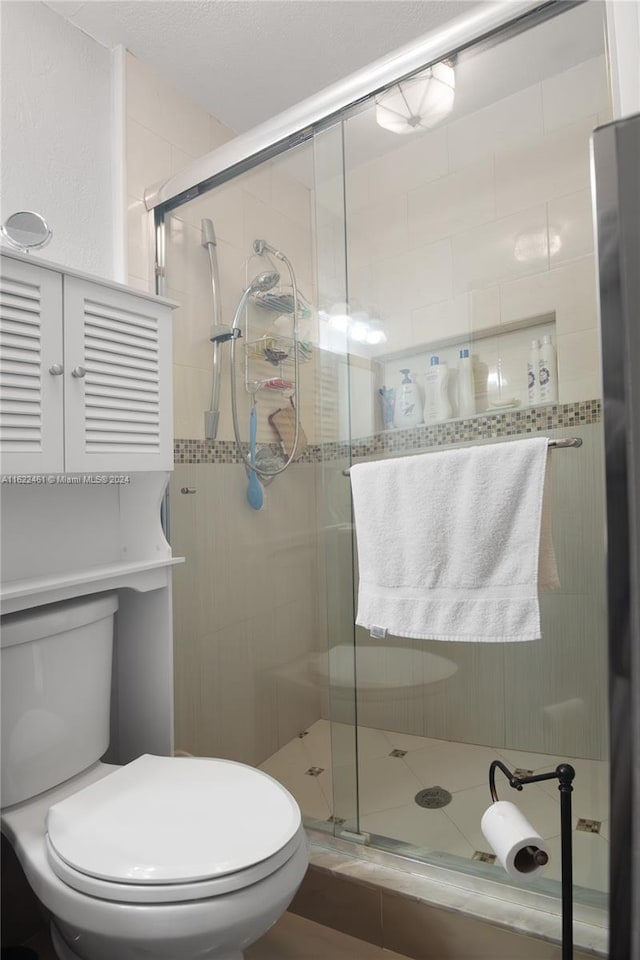 bathroom featuring a shower with door and toilet