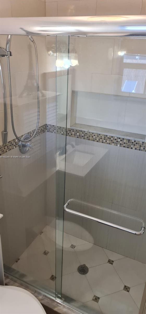 bathroom featuring a shower with shower door and toilet