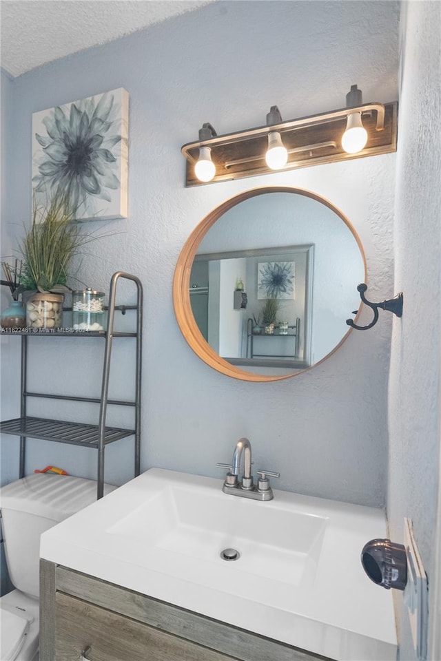 bathroom featuring toilet, a textured ceiling, and vanity