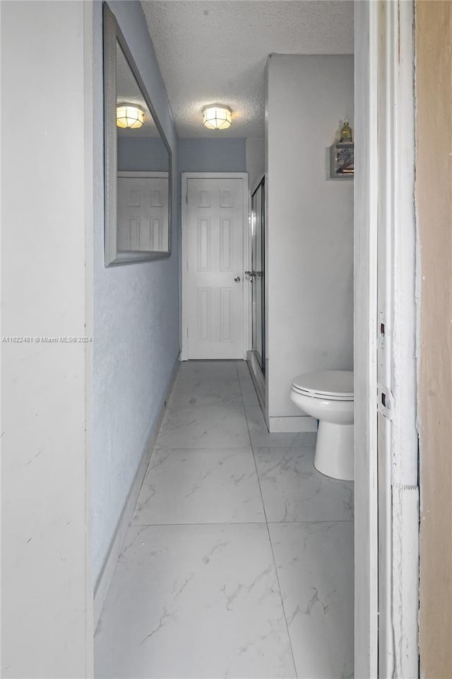 bathroom featuring tile patterned flooring, toilet, and a textured ceiling