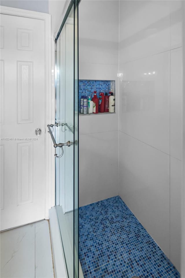 bathroom featuring tile patterned floors and a shower with shower door