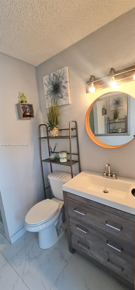 bathroom with a textured ceiling, toilet, vanity, and tile patterned floors