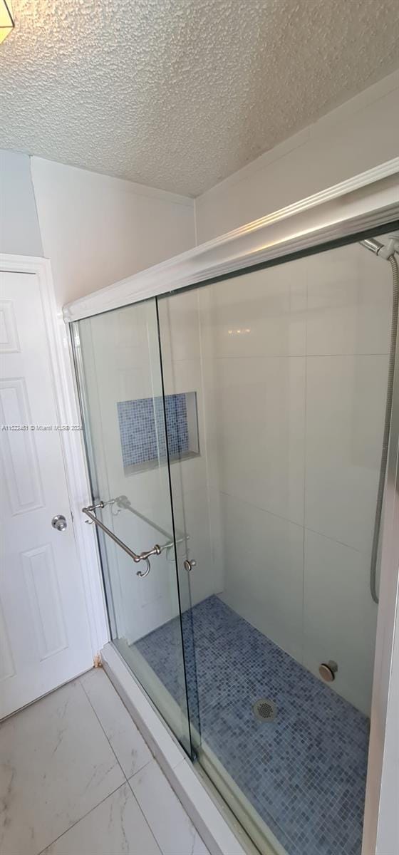 bathroom featuring a textured ceiling, walk in shower, and tile patterned floors