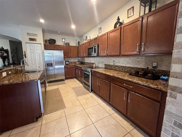 kitchen featuring tasteful backsplash, sink, dark stone countertops, appliances with stainless steel finishes, and light tile patterned floors