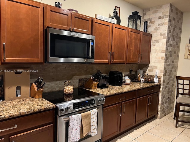 kitchen with stainless steel appliances, light stone countertops, tasteful backsplash, and light tile patterned floors