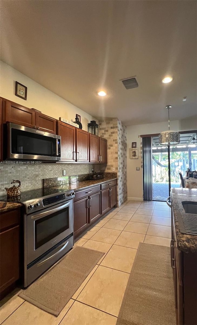 kitchen featuring light tile patterned flooring, tasteful backsplash, stainless steel appliances, and dark stone countertops