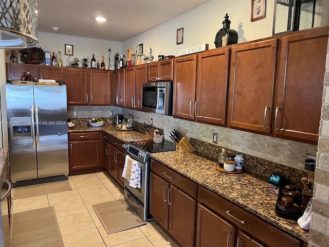 kitchen with dark stone counters, tasteful backsplash, stainless steel appliances, and light tile patterned floors