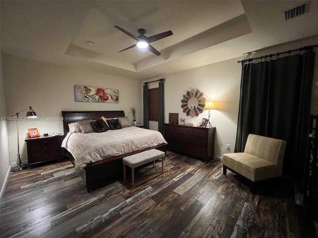 bedroom with ceiling fan, a tray ceiling, and hardwood / wood-style flooring