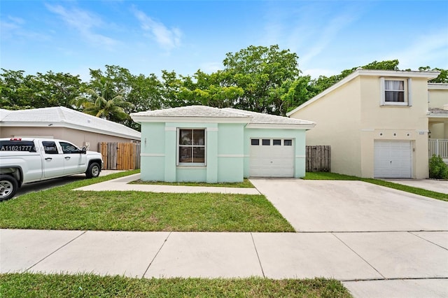 view of front facade with a garage, concrete driveway, a front yard, and stucco siding