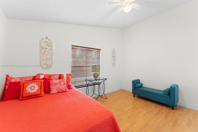 bedroom featuring a ceiling fan, a textured ceiling, baseboards, and wood finished floors