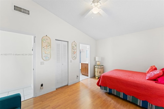 bedroom with light wood-type flooring, ceiling fan, vaulted ceiling, a closet, and ensuite bath