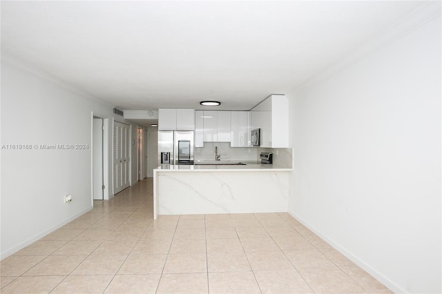 kitchen featuring white cabinets, stainless steel appliances, tasteful backsplash, kitchen peninsula, and light tile patterned floors